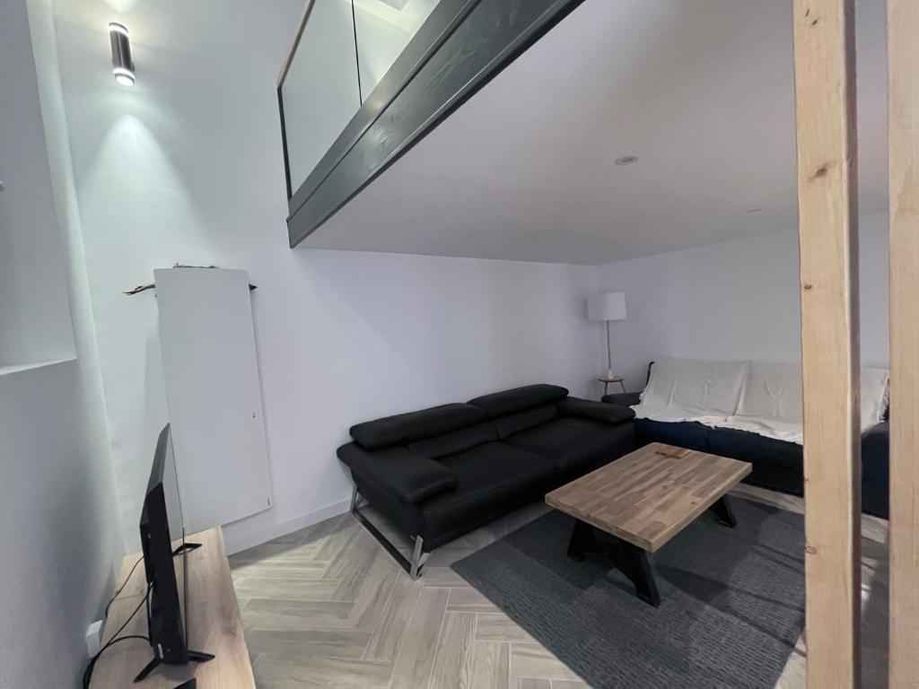 a living room with a black couch and a table at Appartement T3 proche mairie, château, et gare in Rambouillet