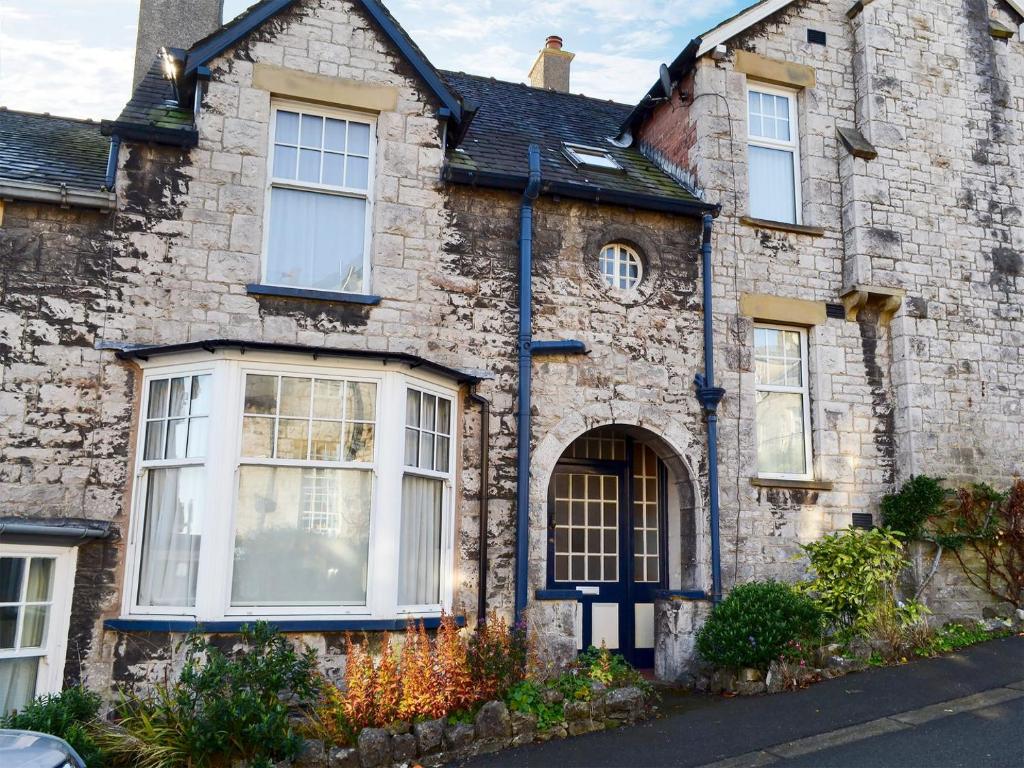 una vecchia casa in pietra con un uomo seduto sul tetto di Lythdene a Grange Over Sands