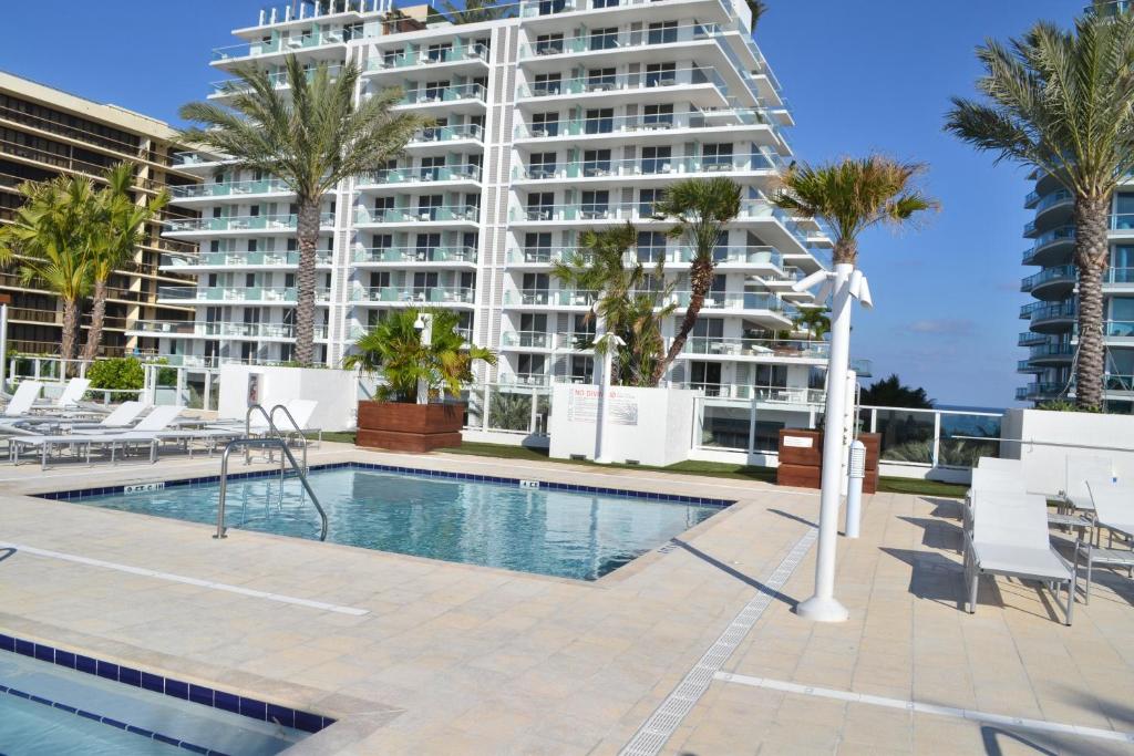 a swimming pool with a large apartment building in the background at Grand Beach Hotel Surfside West in Miami Beach