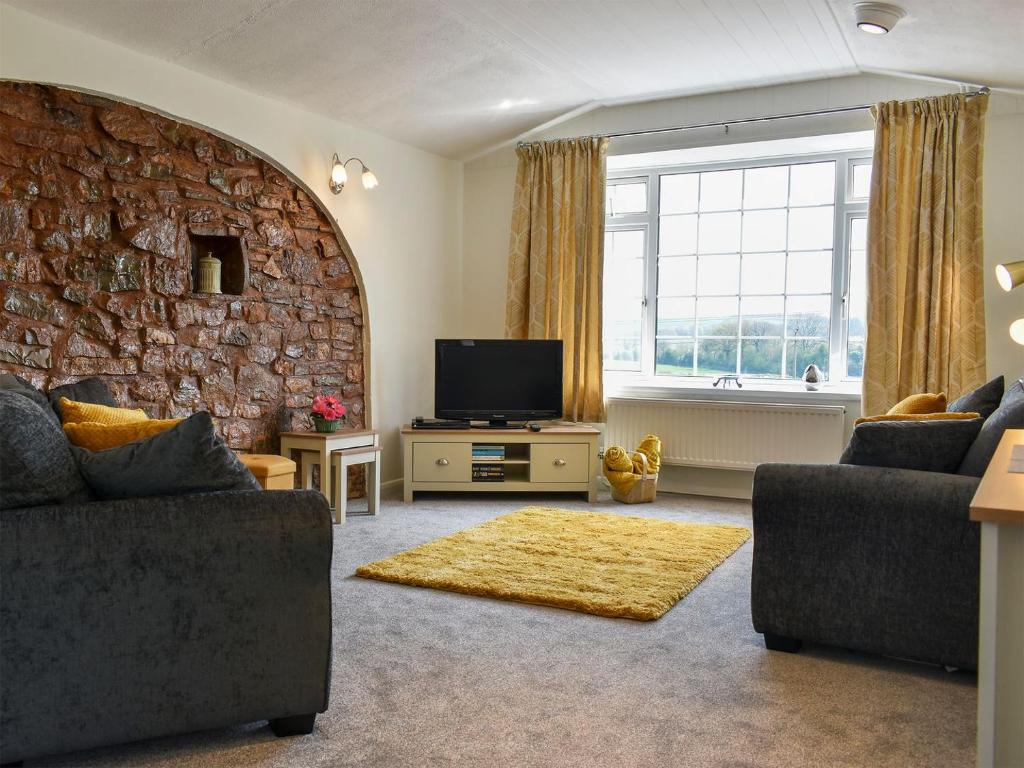 a living room with a stone wall and a television at The Dairy Barn in Burlescombe