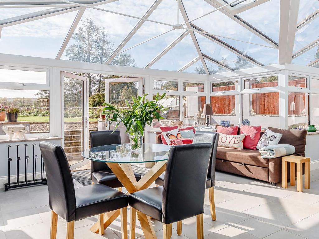a conservatory with a glass table and a couch at Claysun House in Whitecroft