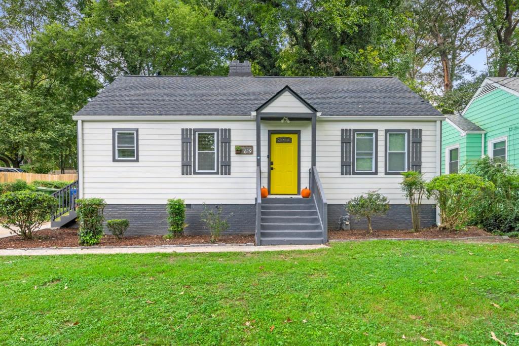 a white house with a yellow door and a yard at Saffron Door Sanctuary, near downtown Atlanta! in Atlanta