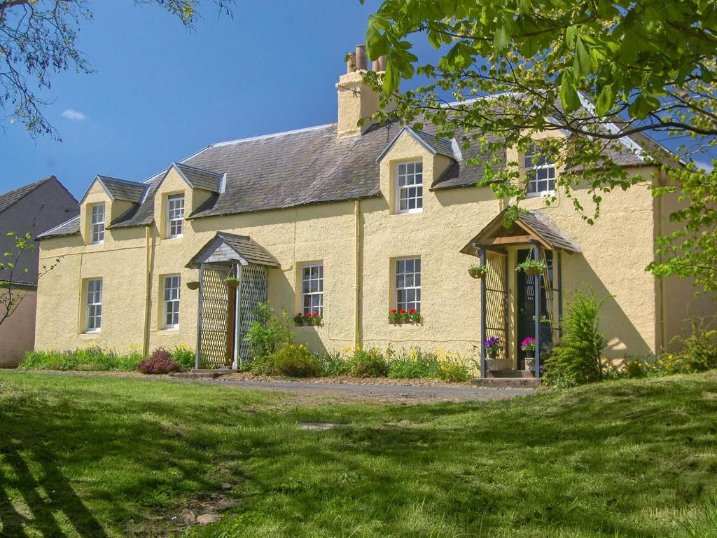 a large yellow brick house with a yard at Avenel Cottage in Town Yetholm