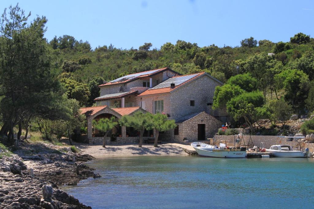 a house on the shore of a river with boats at Seaside secluded apartments Cove Karkavac - Scedro, Hvar - 8801 in Jelsa