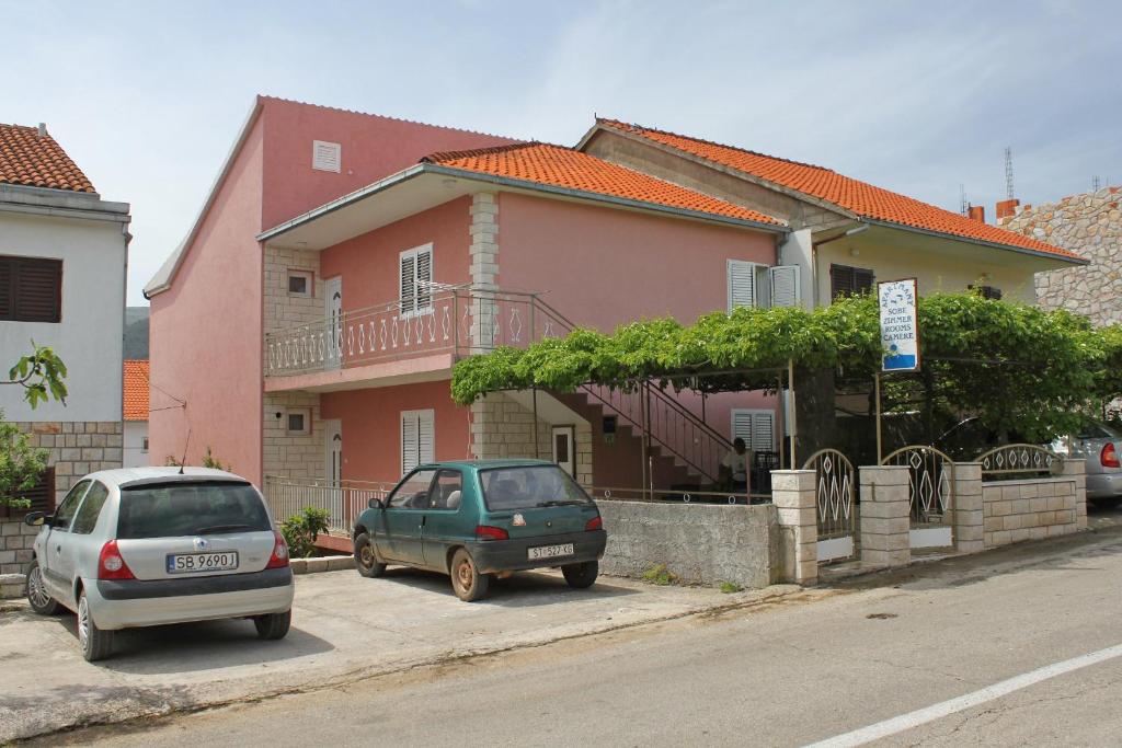dois carros estacionados em frente a uma casa cor-de-rosa em Studio Stari Grad 8726b em Stari Grad