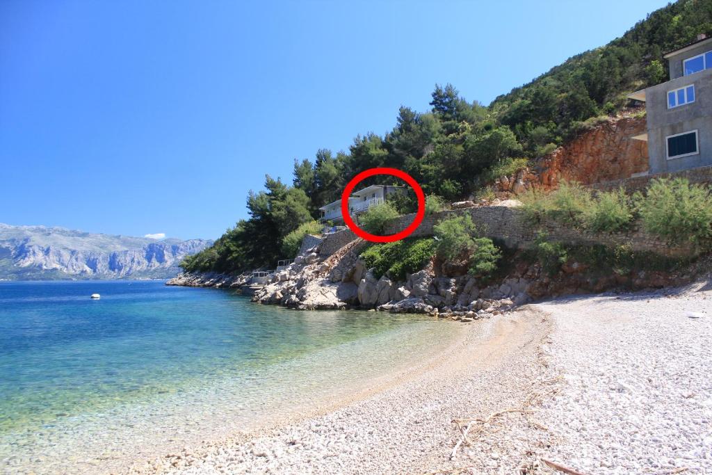 un círculo rojo en una playa junto al agua en Apartments by the sea Cove Mala Pogorila, Hvar - 8953, en Bogomolje