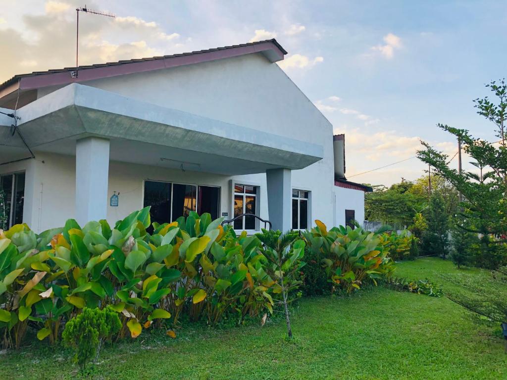 una casa blanca con un arbusto verde delante de ella en Homestay Lestary near Taiping Fast WIFI Netflix, en Taiping