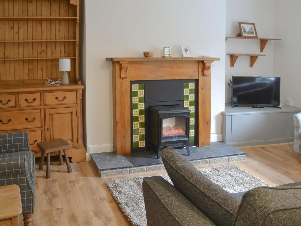 a living room with a fireplace and a couch at Thistle Cottage in Glanton
