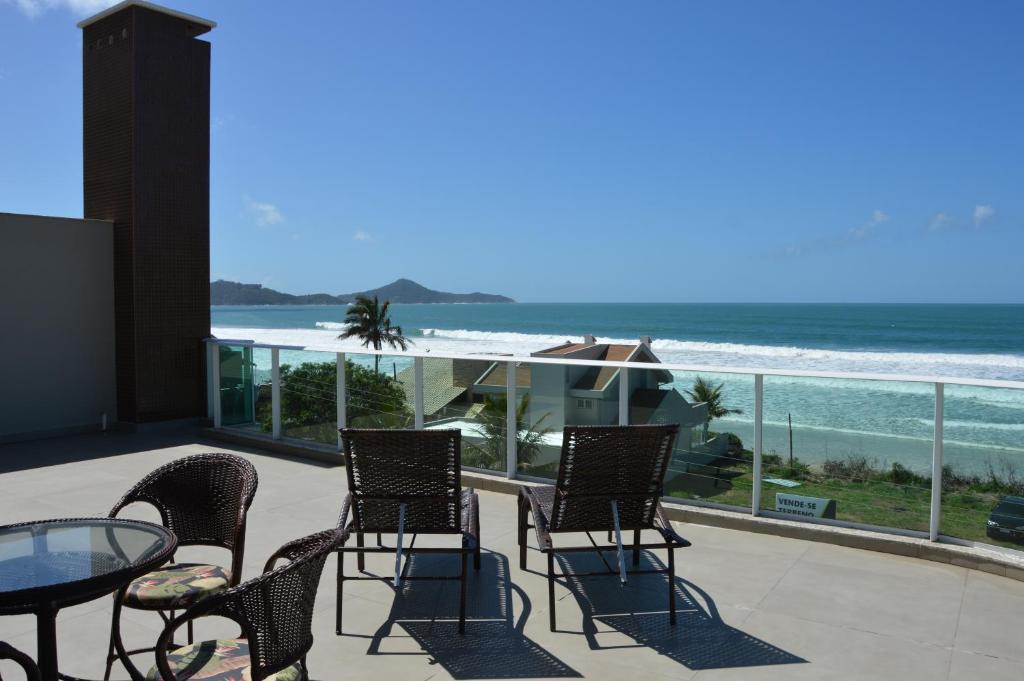 un patio con sillas y una mesa y vistas al océano en Belíssima cobertura duplex - De frente para o mar - Bombinhas-SC, en Bombinhas