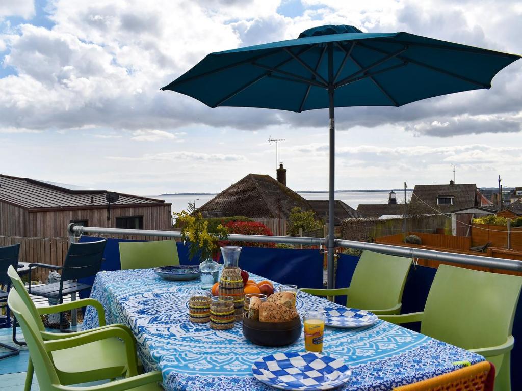 a table with food and an umbrella on a balcony at Fronks House in Harwich