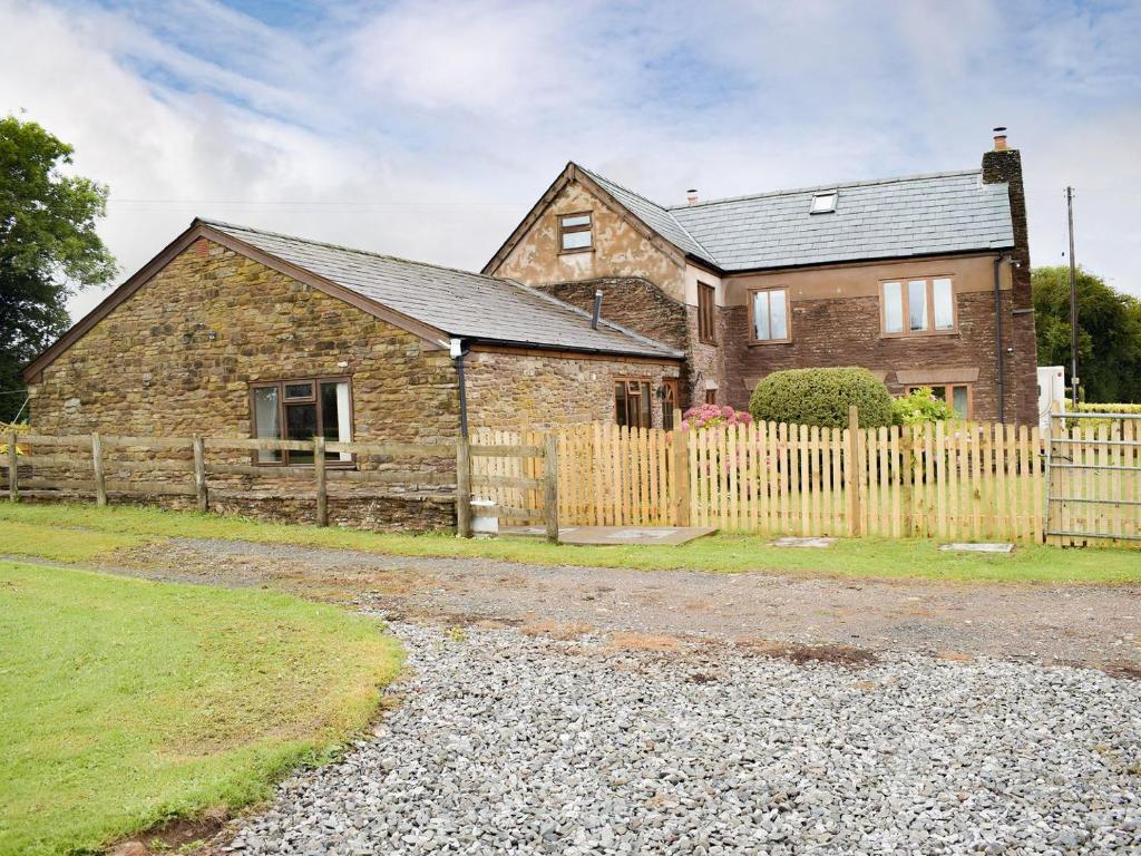 a brick house with a wooden fence in front of it at The Byre in Pencombe