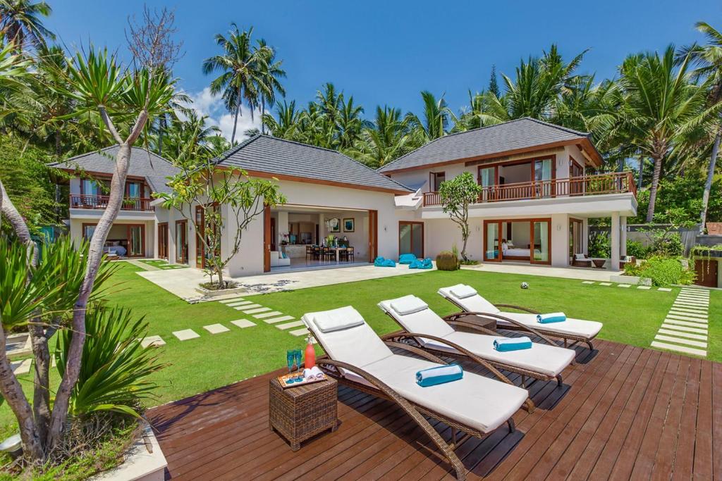 a house with lounge chairs and a backyard at Villa Tirta Nila by Elite Havens in Candidasa