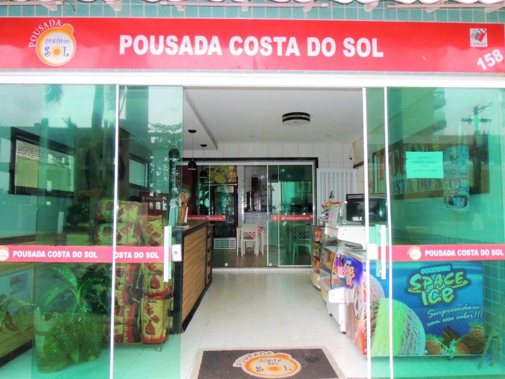 a store with a red sign on the front of it at Pousada Costa Do Sol - By UP Hotel in Praia Grande