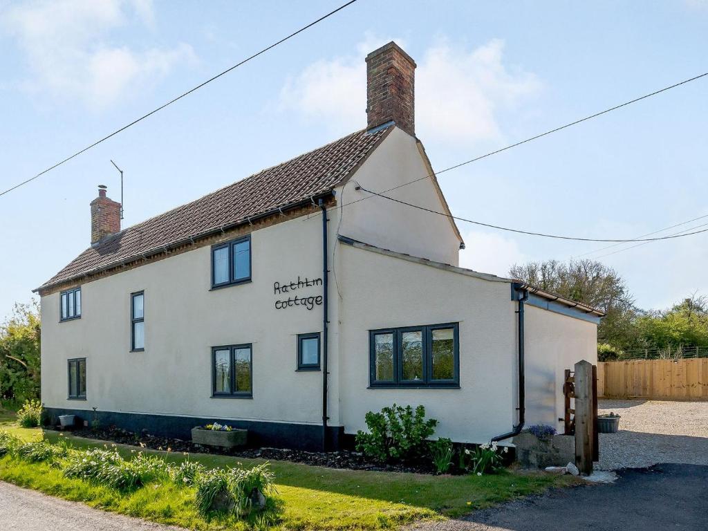 Una casa blanca con un cartel en el costado. en Rathlin Cottage en Cambridge