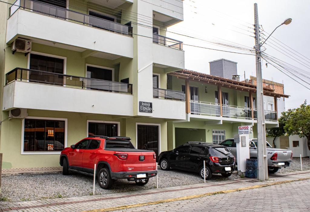 dos coches estacionados frente a un edificio en Residencial Elpidio, en Bombinhas