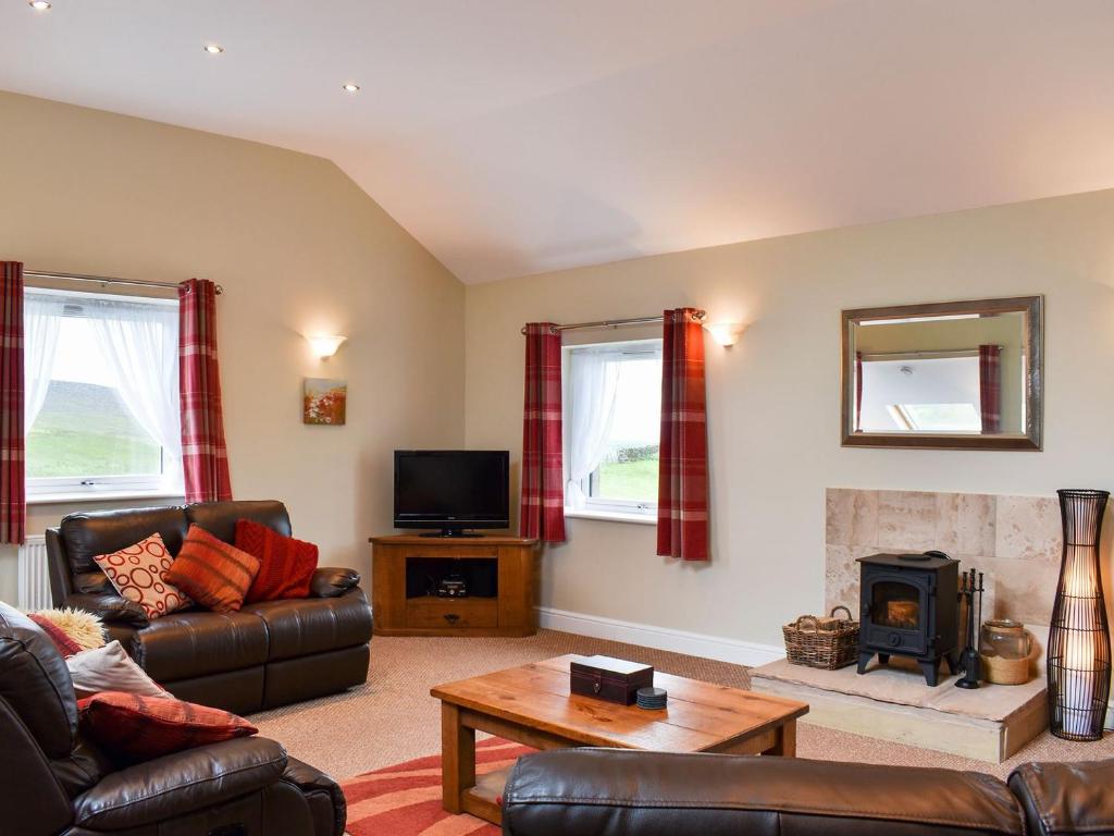 a living room with a couch and a fireplace at Belah Barn in Kirkby Stephen