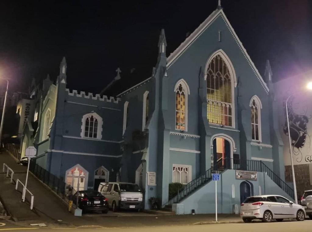 uma igreja azul com carros estacionados lá fora à noite em Chapel Apartments em Dunedin
