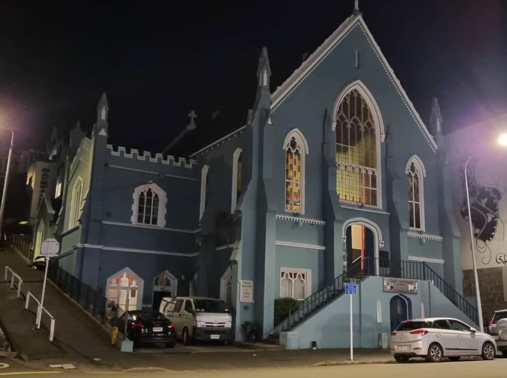 een blauwe kerk met 's nachts geparkeerde auto's bij Chapel Apartments in Dunedin