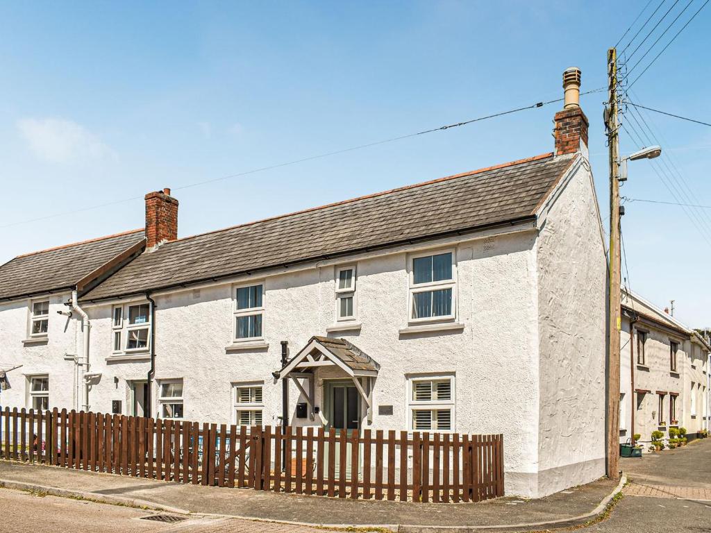 a white brick house with a wooden fence at Chuckle Cottage in Braunton