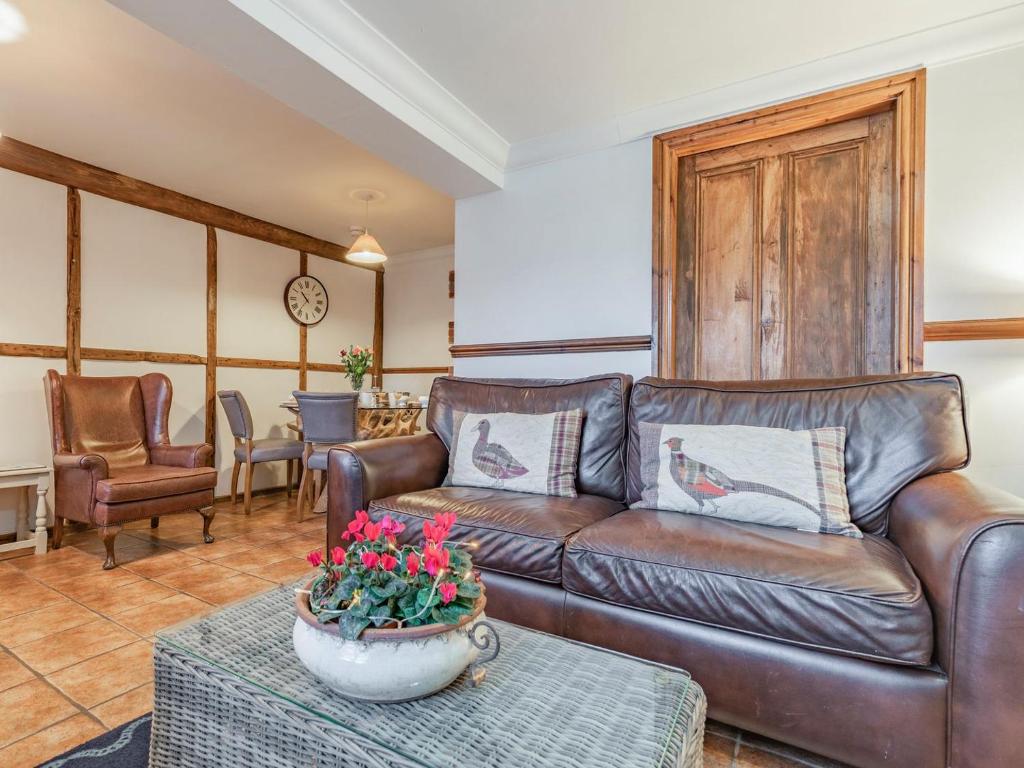 uma sala de estar com um sofá de couro e uma mesa em The Stables - Uk30946 em Barthomley