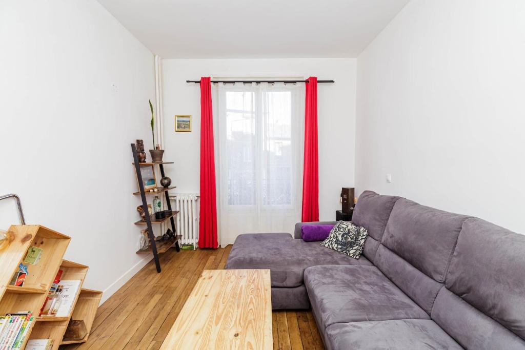 a living room with a gray couch and red curtains at Charming 51m In Aubervilliers in Aubervilliers