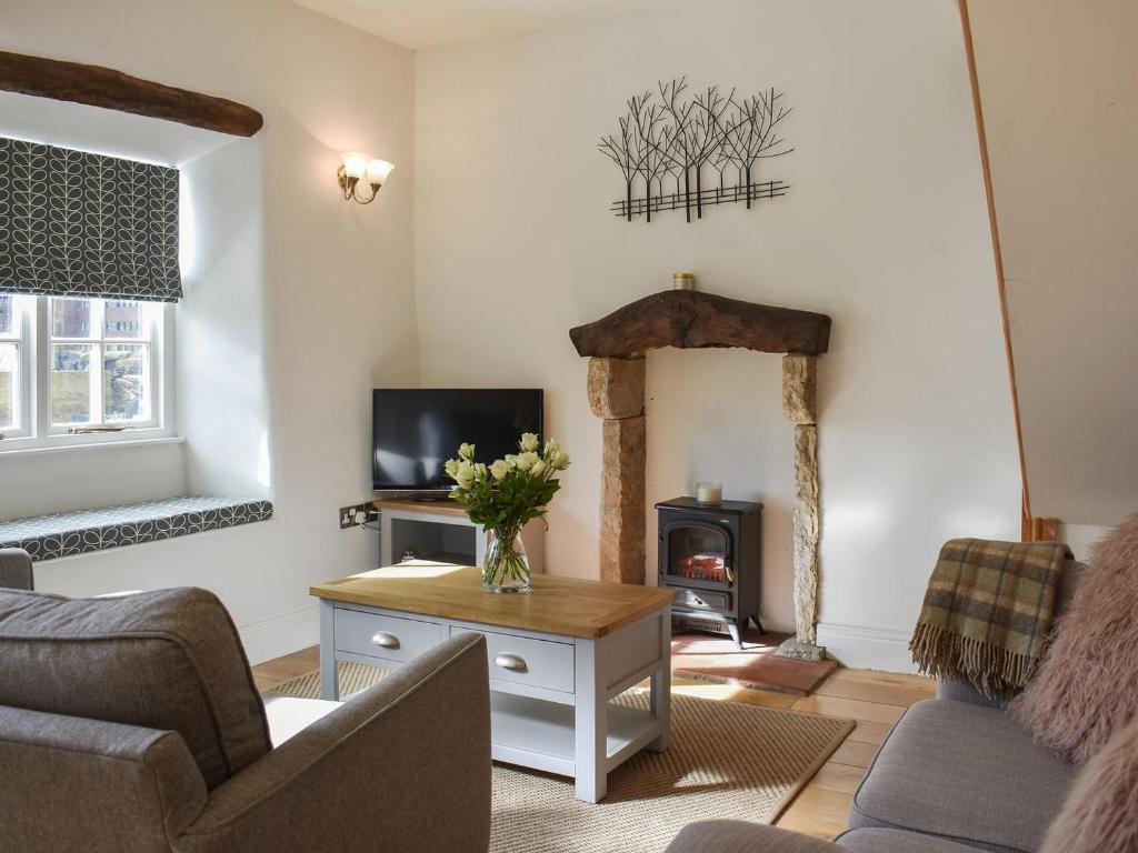 a living room with a couch and a fireplace at Lavender Cottage in Leyburn