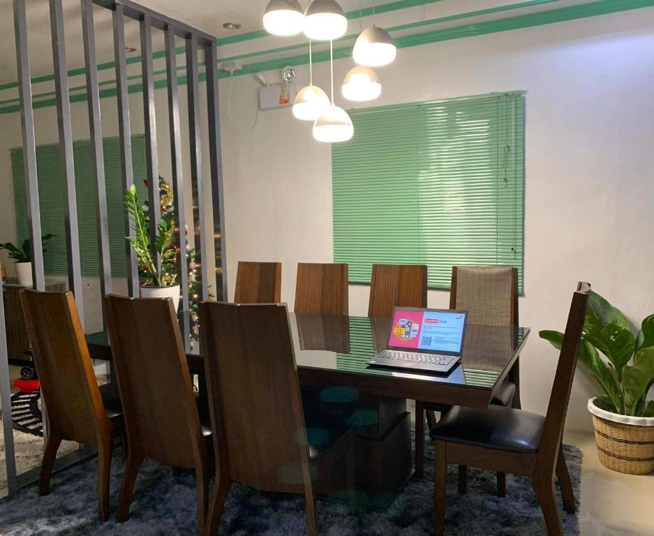 Holiday House near Butuan City Airport في بوتوان: غرفة طعام مع طاولة مع الكمبيوتر المحمول عليها