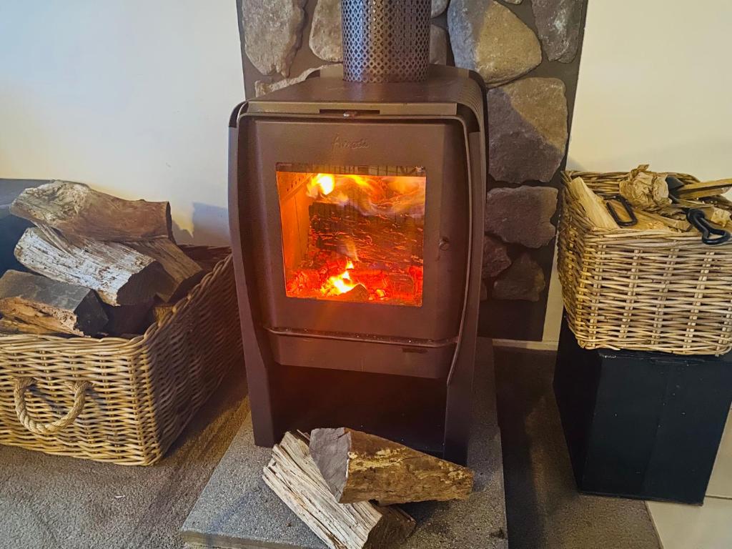 a woodburning stove sitting next to two baskets at ELM Accommodation - Merrijig in Merrijig