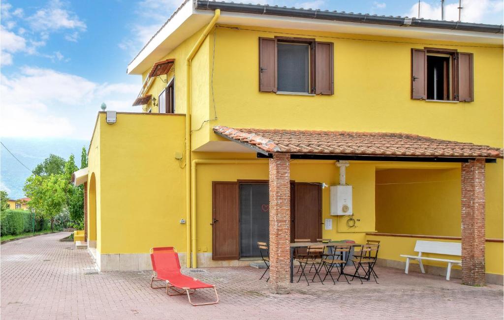 Casa amarilla con sillas rojas y mesa en Gorgeous Home In Carano With Kitchen, en Carano