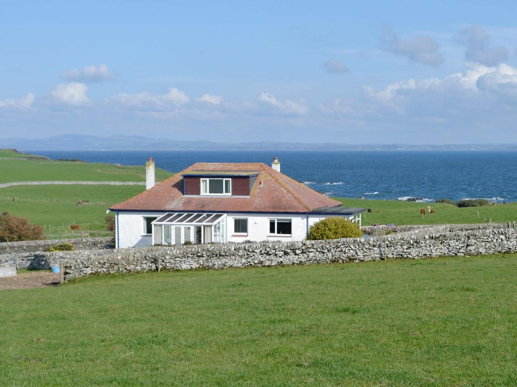 una casa blanca con una pared de piedra junto al océano en Bel-mar en Whithorn