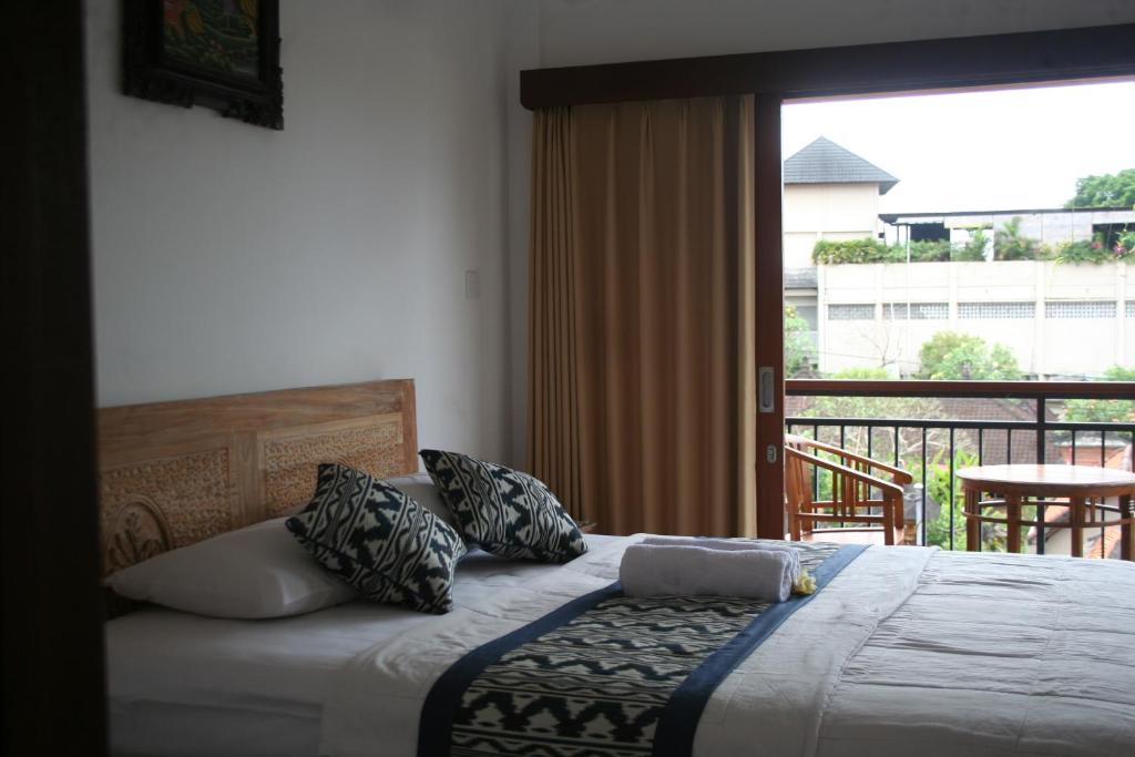 a bedroom with a bed with pillows and a balcony at Run House B&B in Ubud