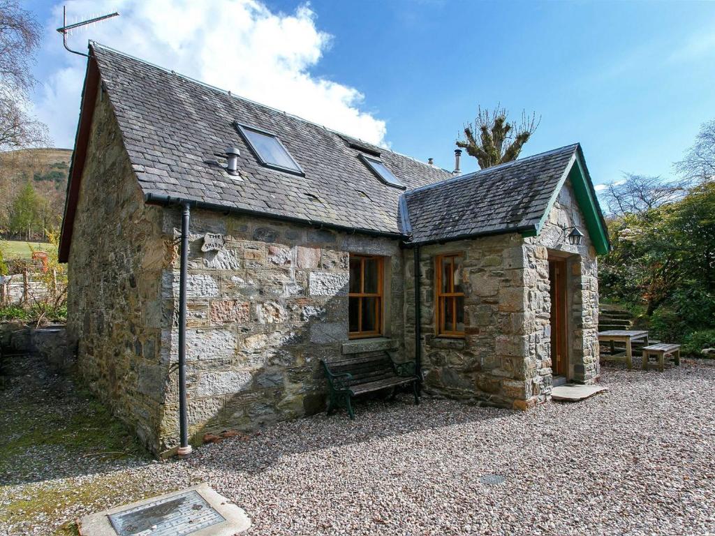 a small stone building with a bench in front of it at The Smiddy - S4278 in Lochearnhead