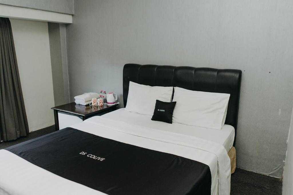 Bett mit schwarzem Kopfteil in einem Hotelzimmer in der Unterkunft DS Colive 34 in Semarang