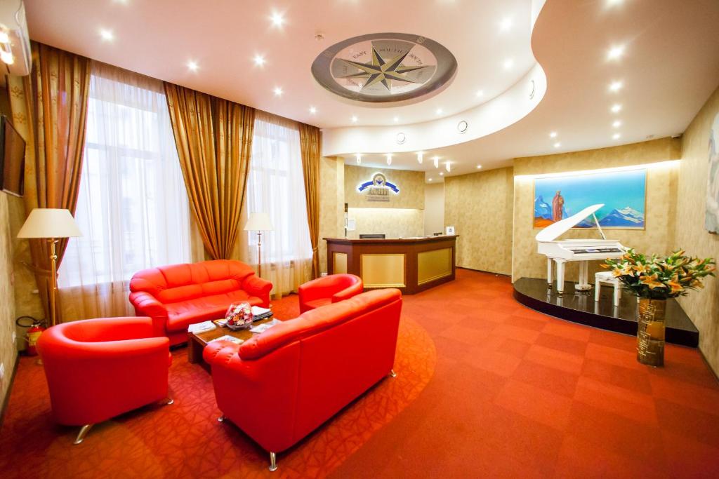 sala de estar con muebles de color rojo y piano en Agni Club Hotel, en San Petersburgo