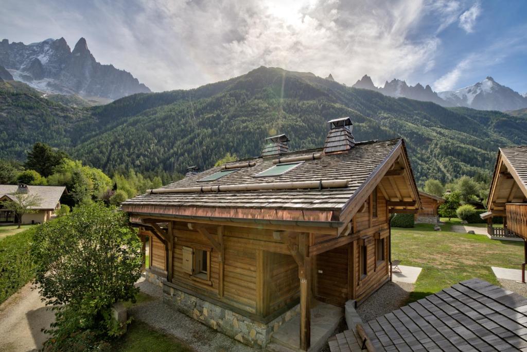 La Cloche des Bois - Alpes Travel - Les Bois - Sleeps 4-6 في شامونيه مون بلان: منزل خشبي صغير مع جبال في الخلفية