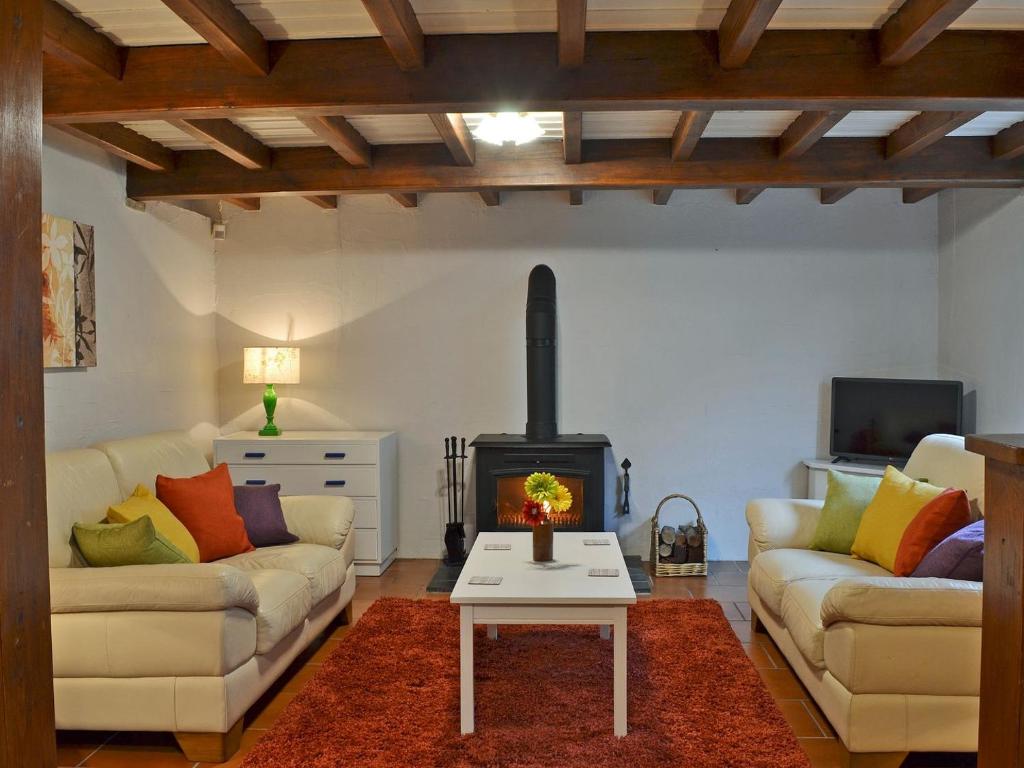 sala de estar con 2 sofás y chimenea en Courtyard Cottage At Dam Hall Barn, en Peak Forest