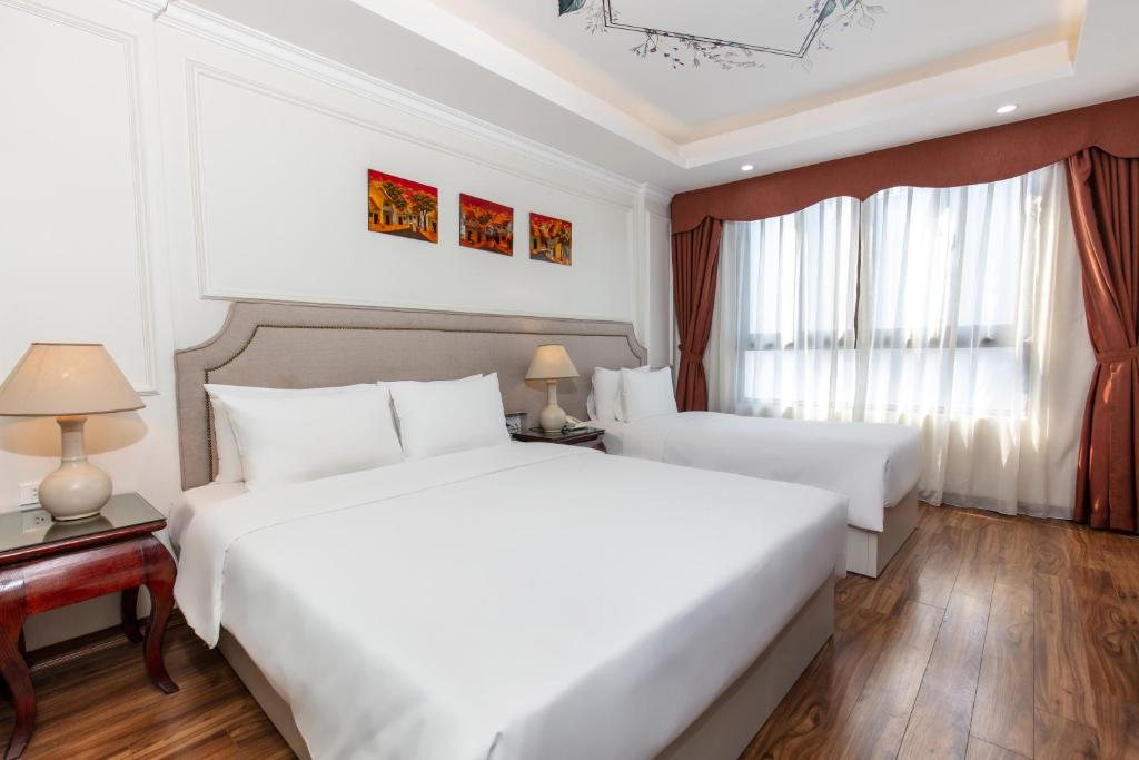 a hotel room with two beds and a window at Golden Legend Palace Hotel in Hanoi