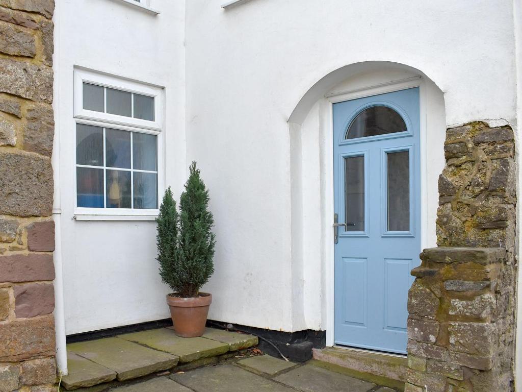 a house with a blue door and a potted plant at The Granary in Huntley