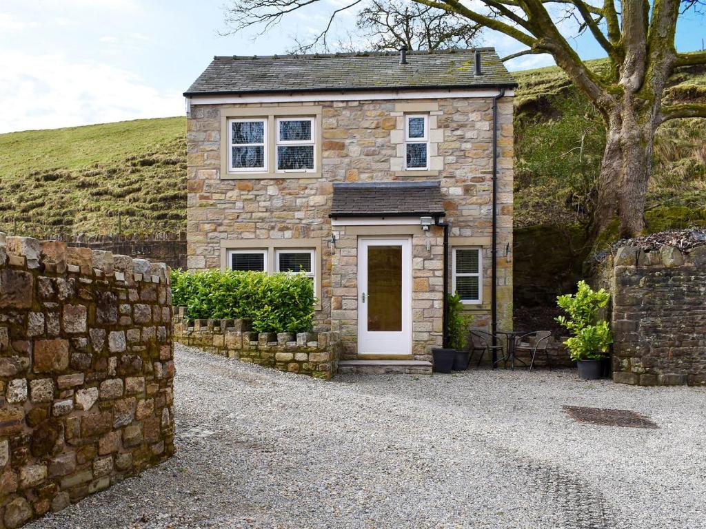 a stone house with a white door and a stone wall at Swaledale Cottage - Barley Green Mill in Barrowford