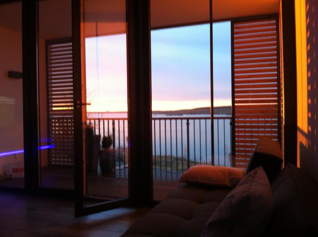 ein Wohnzimmer mit Sofa und Blick auf einen Balkon in der Unterkunft Ferienwohnung Seeblick Zwenkau in Zwenkau
