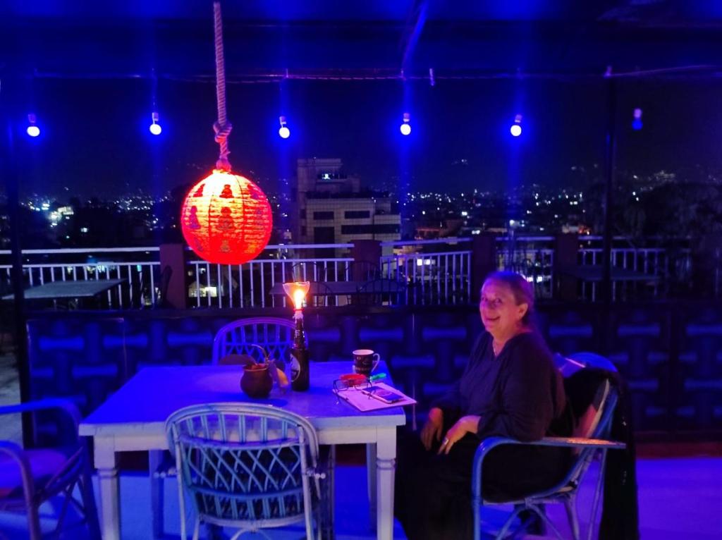 una mujer sentada en una mesa con una lámpara encendida en Hotel Hikers Haven, en Katmandú