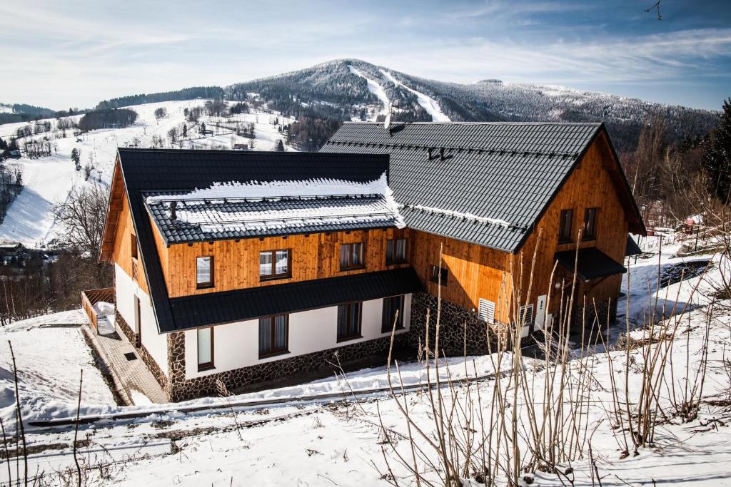 una casa en la nieve con una montaña en el fondo en Penzion Kozel - Herlíkovice Krkonoše, en Vrchlabí