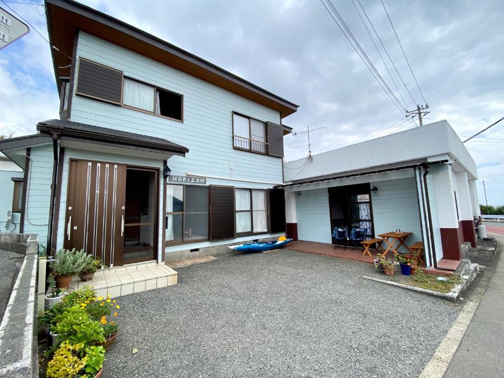 una casa blanca con una entrada delante de ella en ホライゾン en Oshima