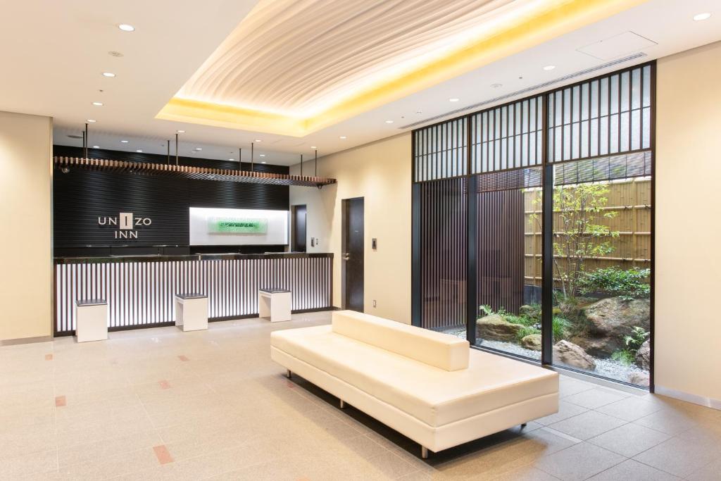 a lobby with a white couch and a large screen at UNIZO INN Kanazawa Hyakumangoku Dori in Kanazawa