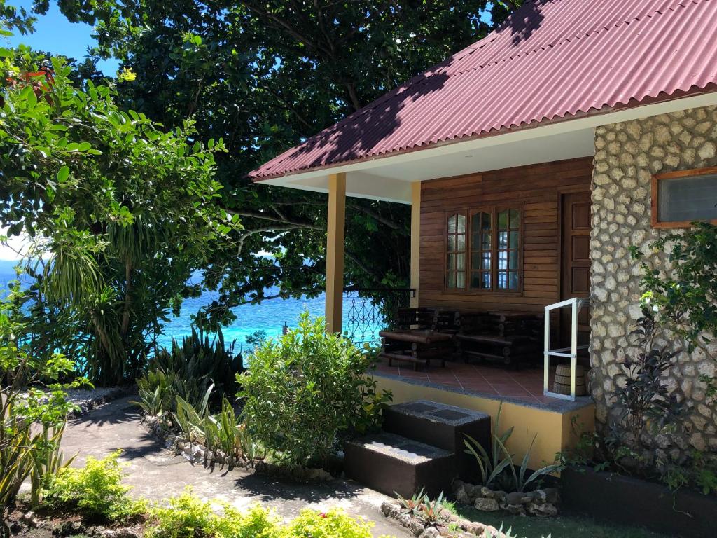 una pequeña casa con techo rojo junto al agua en Tipolo Beach Resort, en Moalboal
