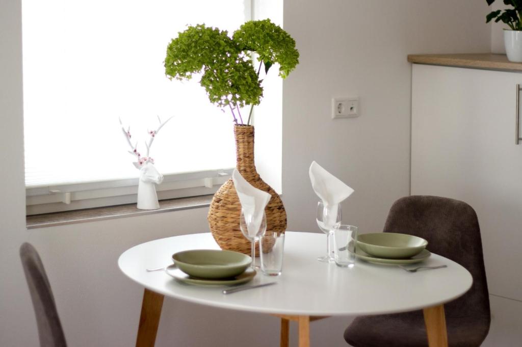 une table blanche avec deux chaises et un vase avec des plantes dans l'établissement Pfeffer's kleine Ferienwohnung, à Bad Lauterberg