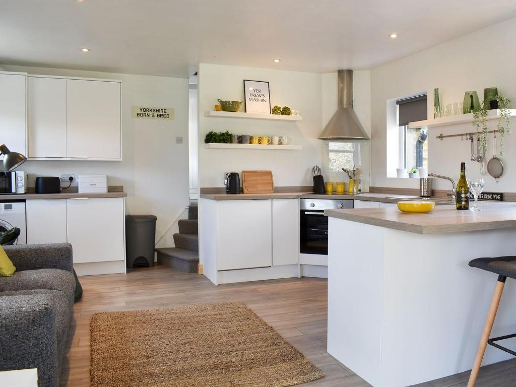 a kitchen with white cabinets and a counter top at Little Plumtree in Addingham