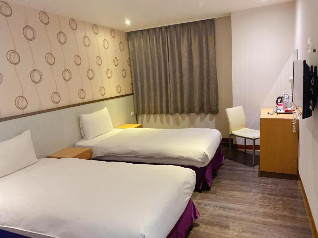 a hotel room with two beds and a desk at Centre Hotel in Kaohsiung