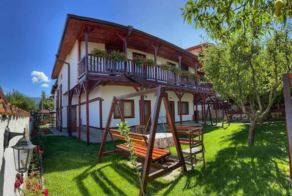a house with a porch and a swing in the yard at Medi Guest House in Sapareva Banya