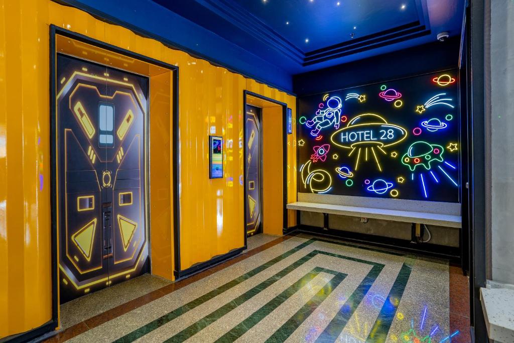 a hallway with two doors with neon signs on the wall at Hotel 28 Chow Kit Kuala Lumpur in Kuala Lumpur